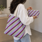 Woman carrying the lilac striped tote bag next to the matching makeup bag