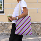 Woman walking with the lilac diagonal striped tote bag on her shoulder and an iced drink