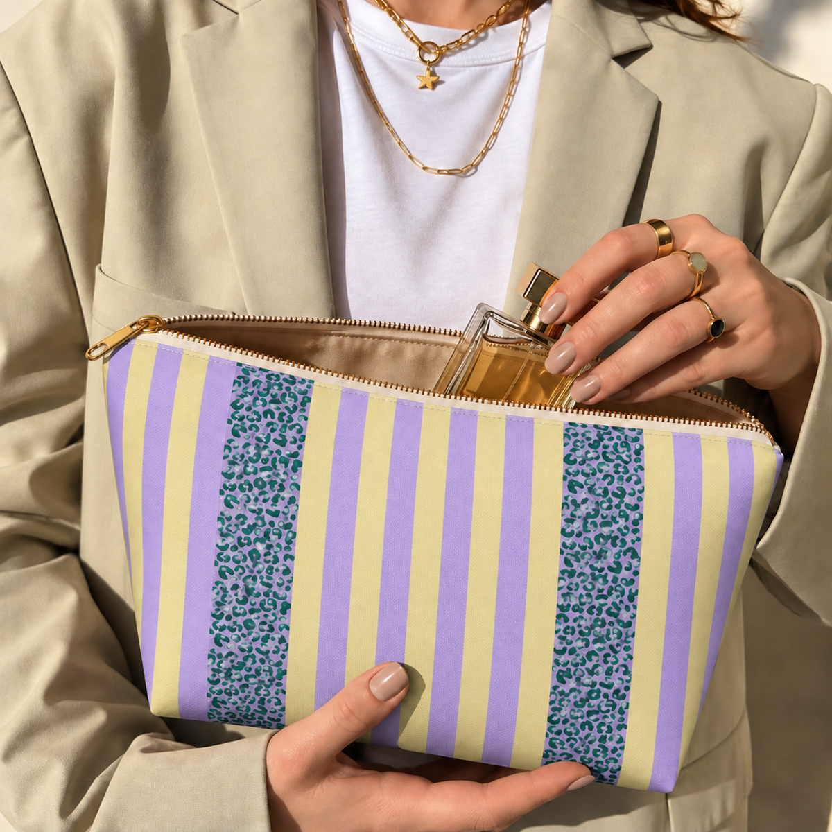Hands holding the open Lilac Leopard Striped makeup bag filled with cosmetics