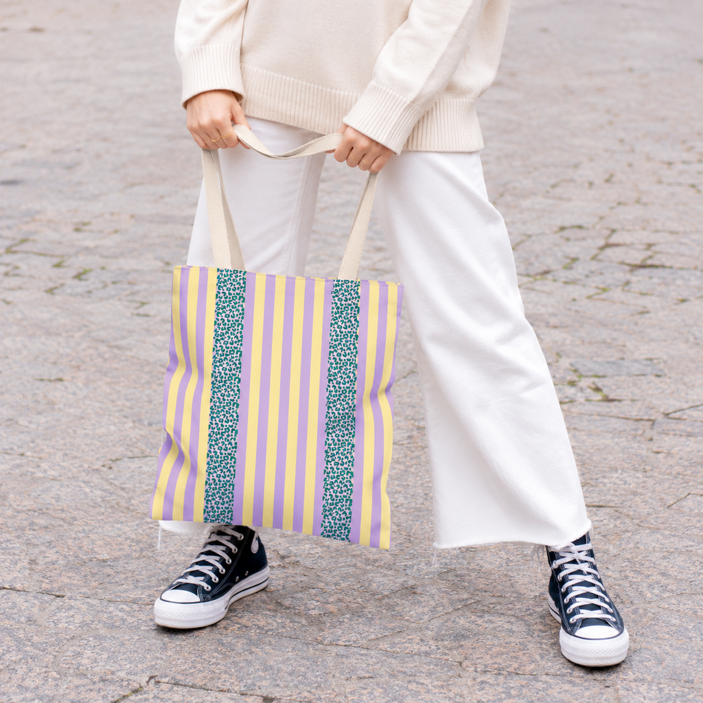 Model in white trousers carrying the Lilac Leopard Striped tote bag with blue leopard panel
