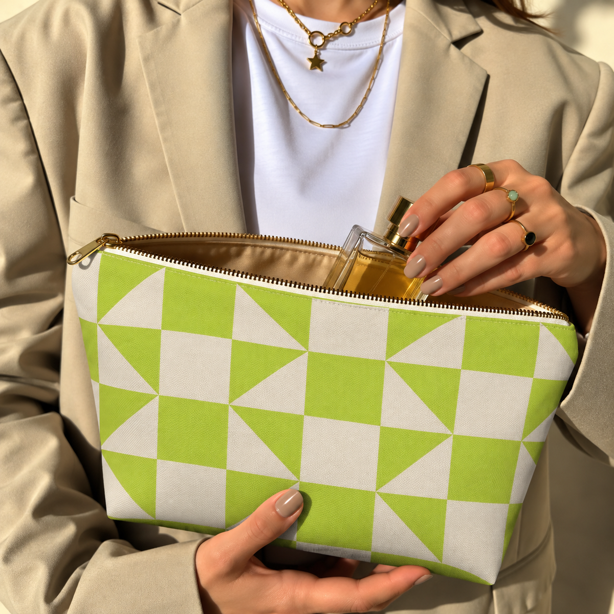 Woman holding the lime green cream geometric makeup bag open with the gold zipper