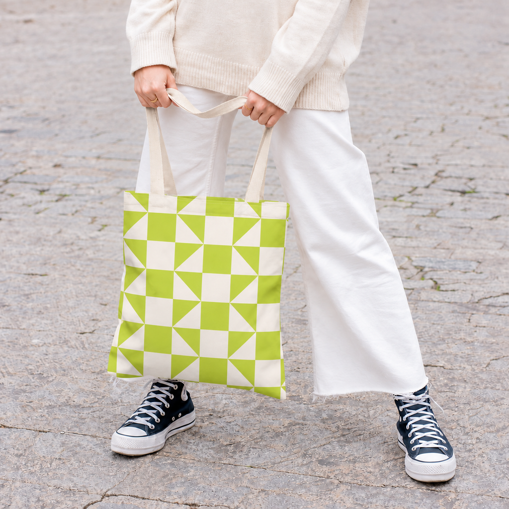 Woman in white trousers holding the lime green cream geometric tote bag by the handles