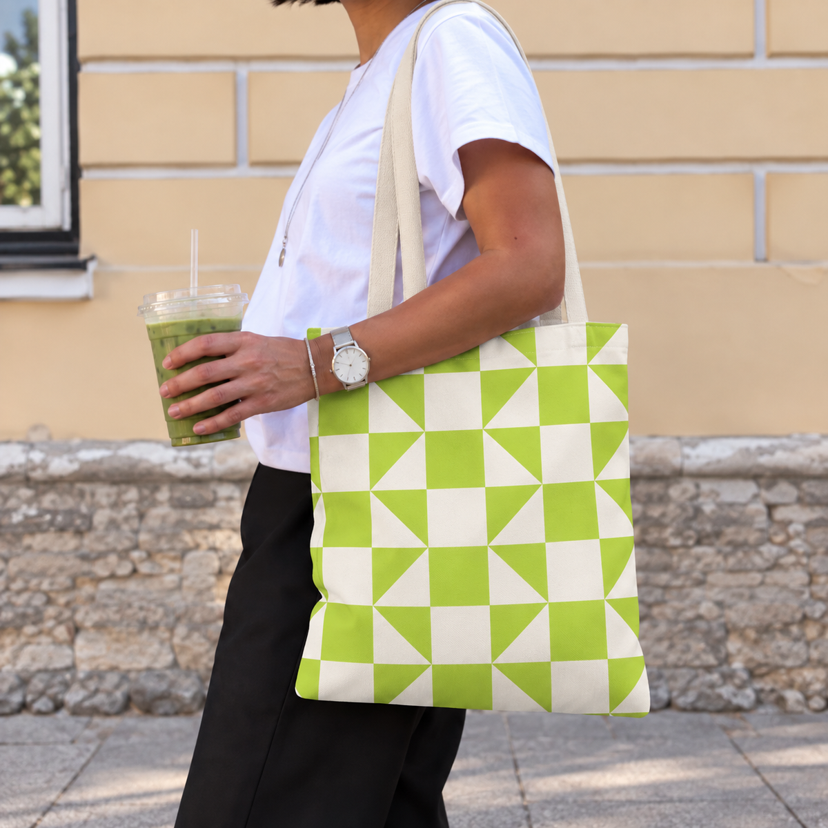 Woman carrying the lime green cream geometric tote bag on her shoulder while holding a drink