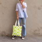 Woman standing in jeans and a white shirt with the lime green cream geometric tote bag