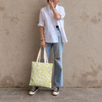 Woman in jeans and sneakers holding the lime green leopard print tote bag
