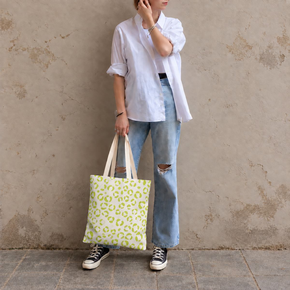 Woman in jeans and sneakers holding the lime green leopard print tote bag