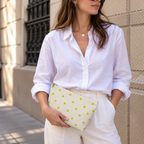 Woman in a white shirt holding the polka dot makeup bag as a clutch