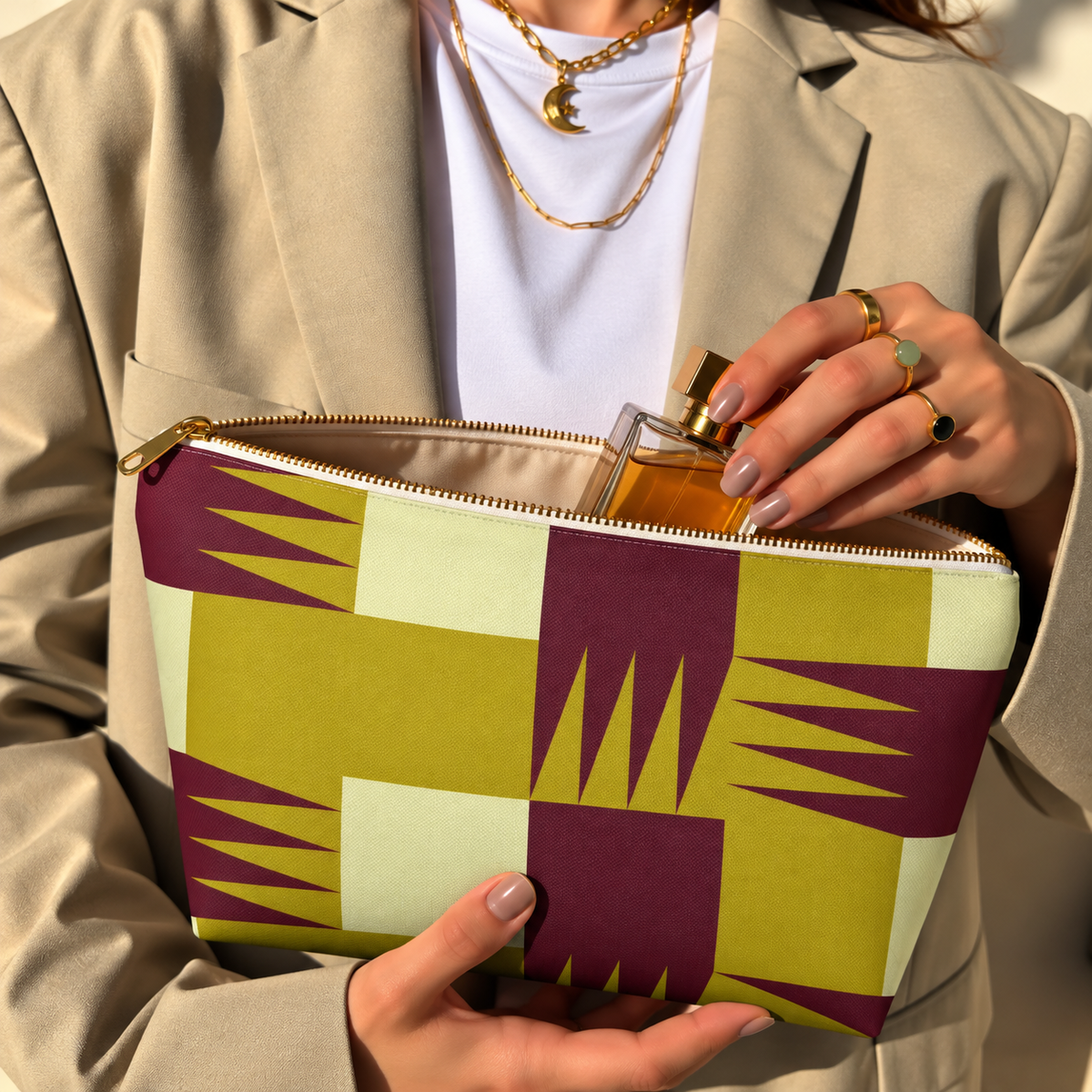 Model opening the mustard burgundy geometric makeup bag to take out a perfume bottle