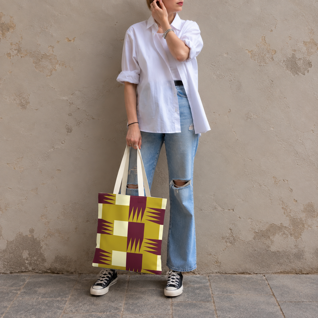 Model in jeans standing with the geometric tote bag in mustard and burgundy