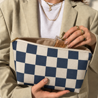 Hands holding the open navy cream checkered makeup bag