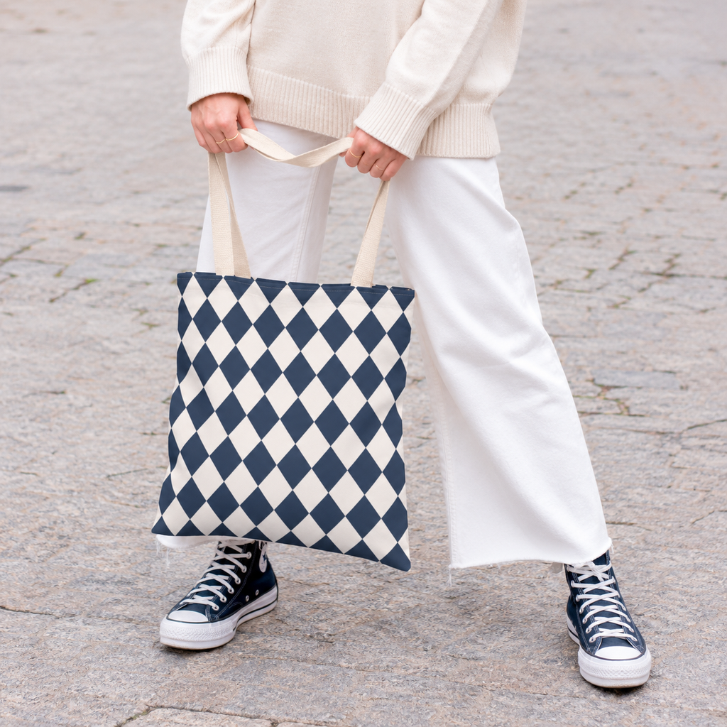 Woman holding a navy cream diamond checkered tote bag with white trousers and sneakers