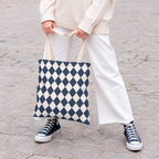Woman holding a navy cream diamond checkered tote bag with white trousers and sneakers