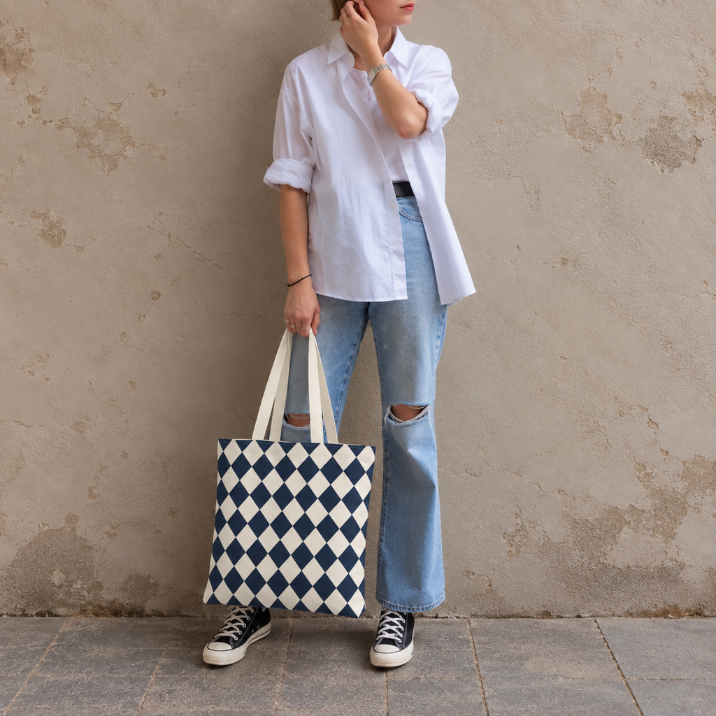 Woman leaning on a wall holding a navy diamond checkered tote bag
