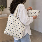 Model carrying the polka dot tote bag while holding the matching navy cream makeup bag