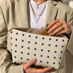 Woman opening the navy cream polka dot makeup bag to take out a perfume bottle