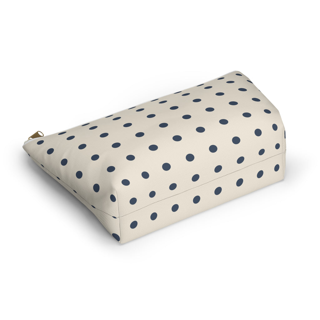 Cream cosmetic bag with small navy polka dots lying at an angle