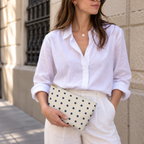 Woman in a white shirt holding the navy cream polka dot makeup bag at her hip