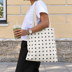 Side view of a woman wearing the navy cream polka dot tote bag on her shoulder