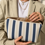 Hands holding the open navy cream striped makeup bag