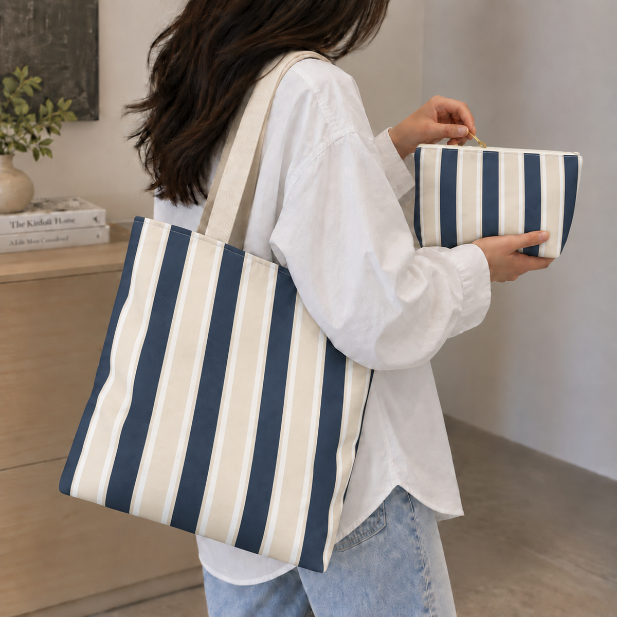 Woman wearing the navy cream striped tote bag with the matching makeup bag in her hand