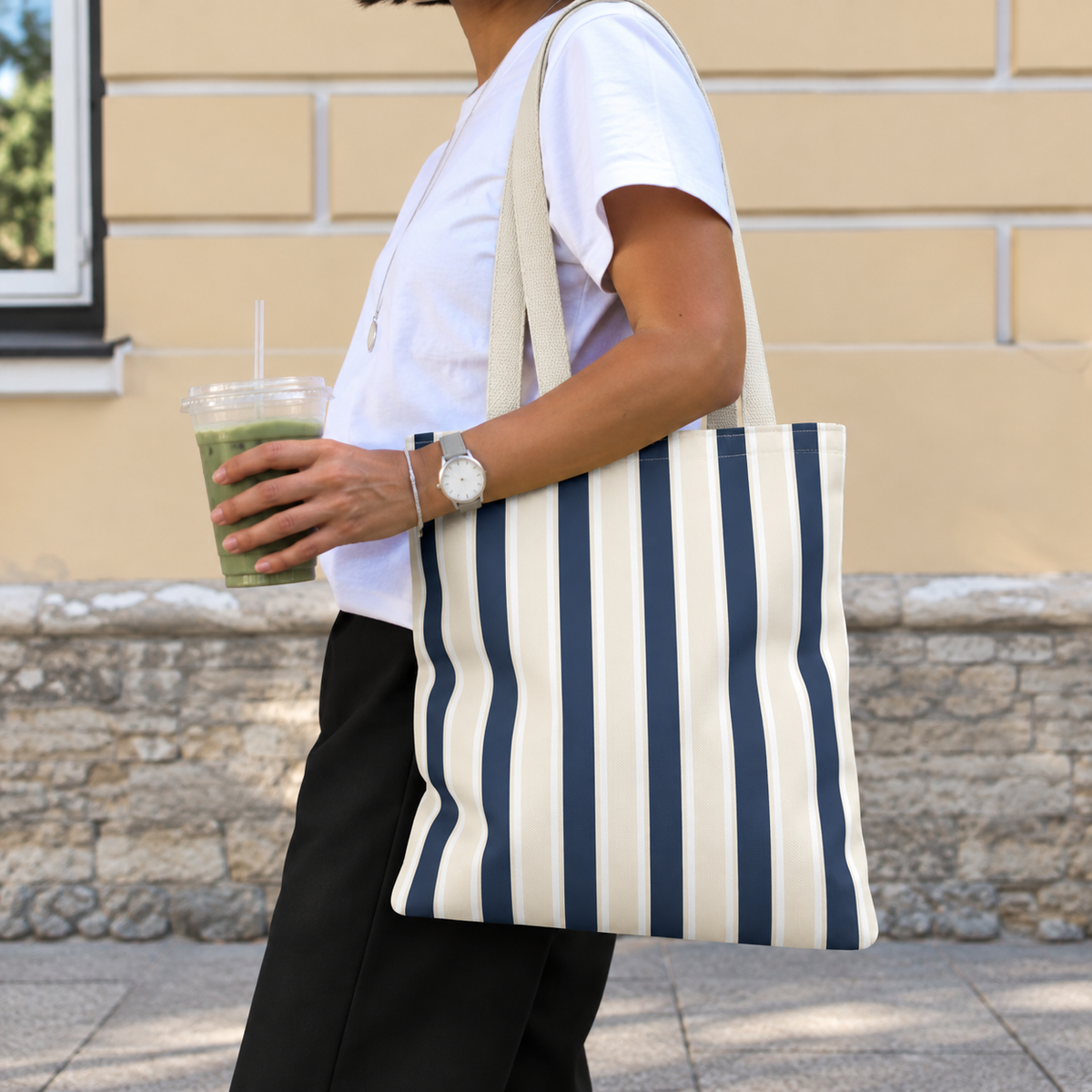 Woman carrying the navy cream striped tote bag on her shoulder on the street