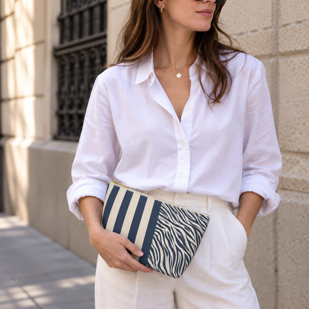 Woman in a white blouse holding a navy cream zebra striped makeup bag