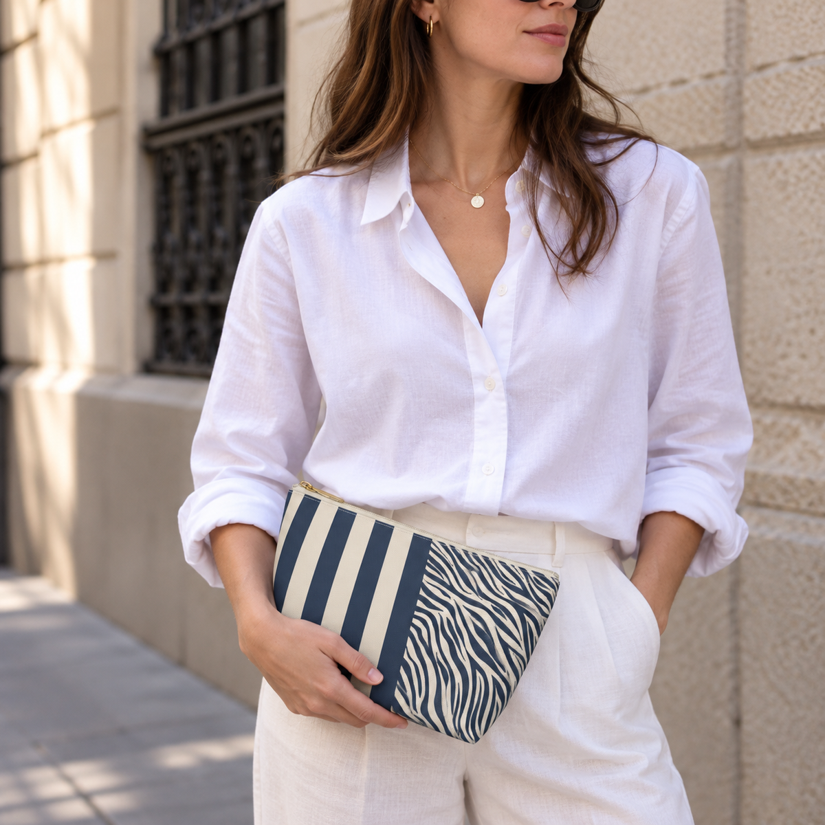 Woman in a white blouse holding a navy cream zebra striped makeup bag