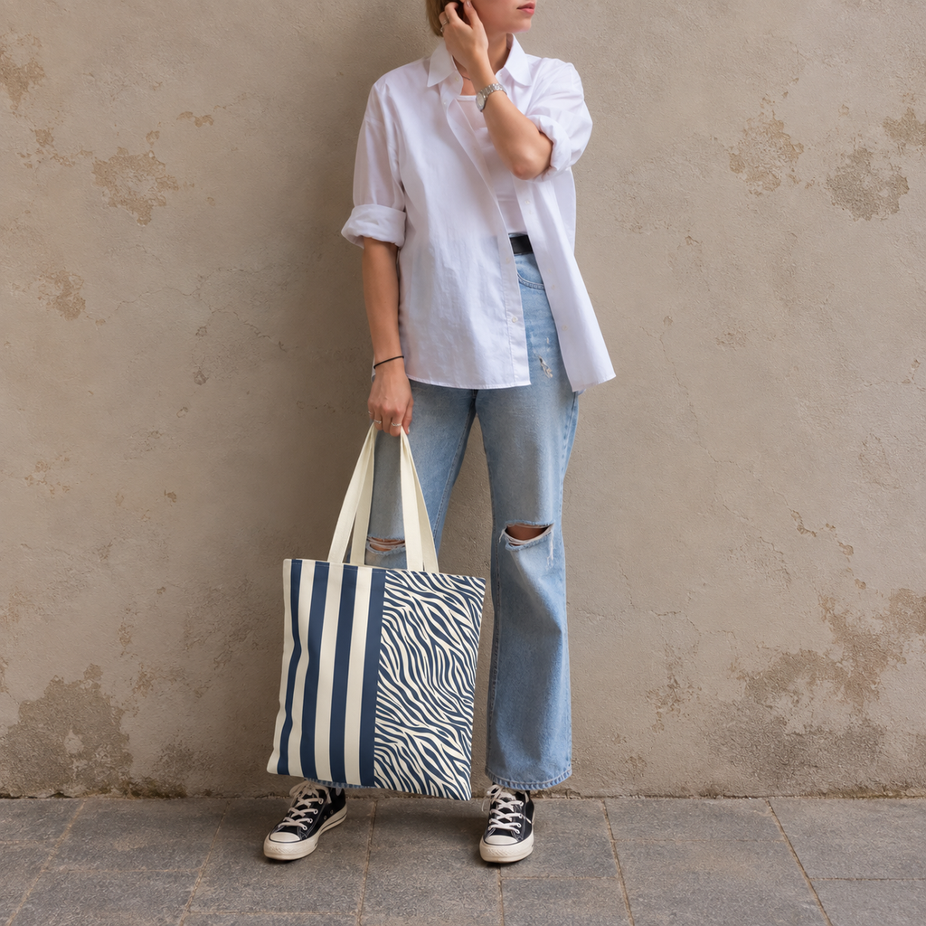 Woman leaning on a wall holding a navy cream zebra striped tote bag