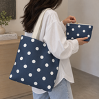 Model carrying the polka dot tote bag while holding the matching navy makeup bag