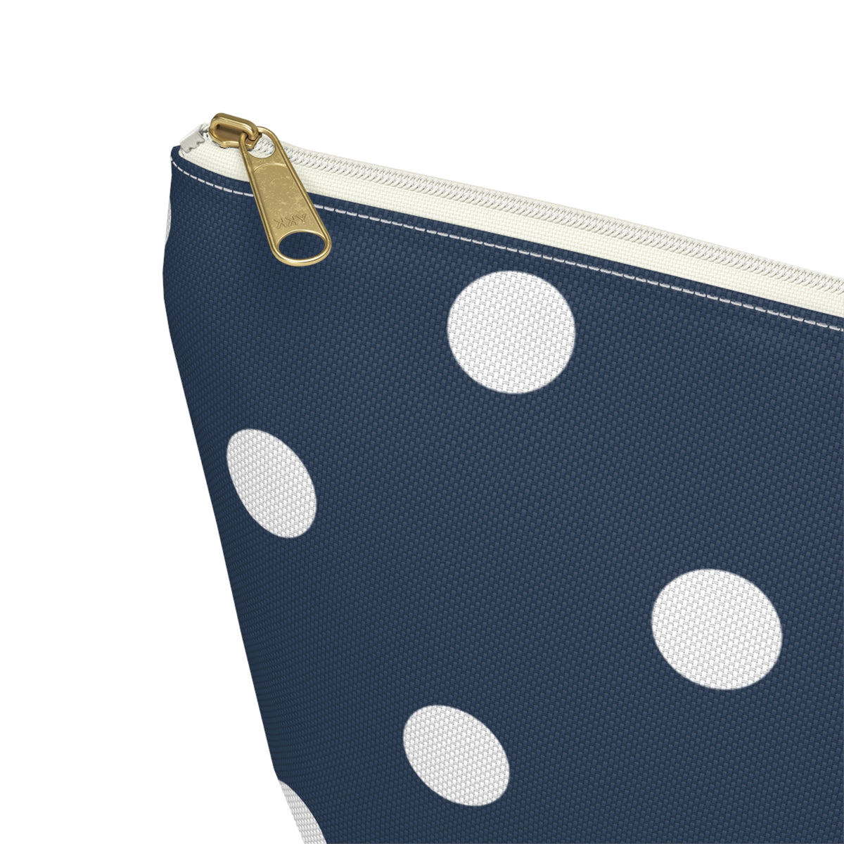 Close-up of the gold zipper pull on the navy white polka dot makeup bag