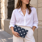 Woman in a white shirt holding the navy polka dot makeup bag at her hip