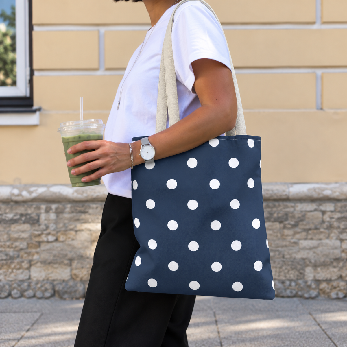 Side view of a woman wearing the navy white polka dot tote bag on her shoulder
