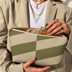 Model in a beige blazer taking a product out of the open olive beige geometric makeup bag