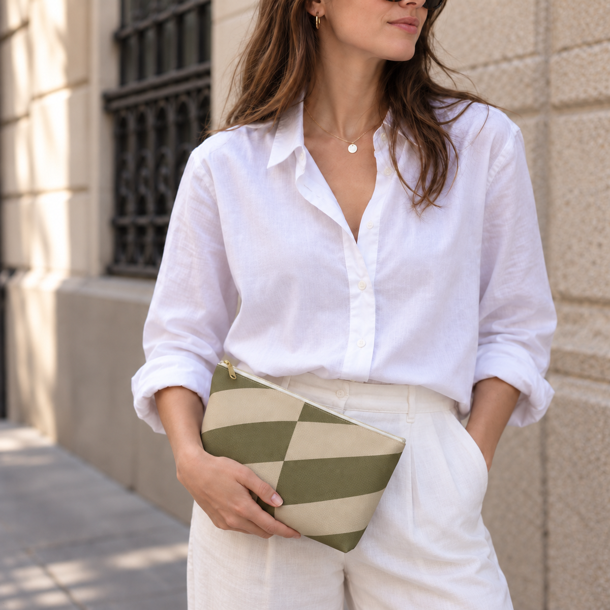 Model in a white shirt holding the olive beige geometric makeup bag as a clutch