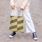 Model holding the olive beige geometric tote bag in front of white trousers