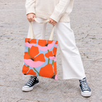 Model holding the orange poppy floral tote bag by its handles