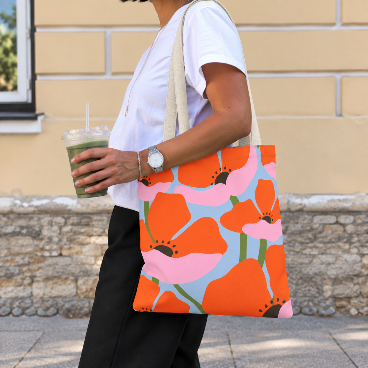 Woman with an iced drink wearing the orange poppy floral tote bag on her shoulder