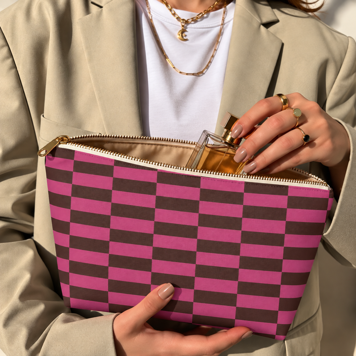 Woman holding the pink brown checkered makeup bag open with the gold zipper