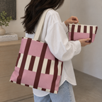 Woman carrying the pink burgundy cream striped tote bag while holding the matching makeup bag