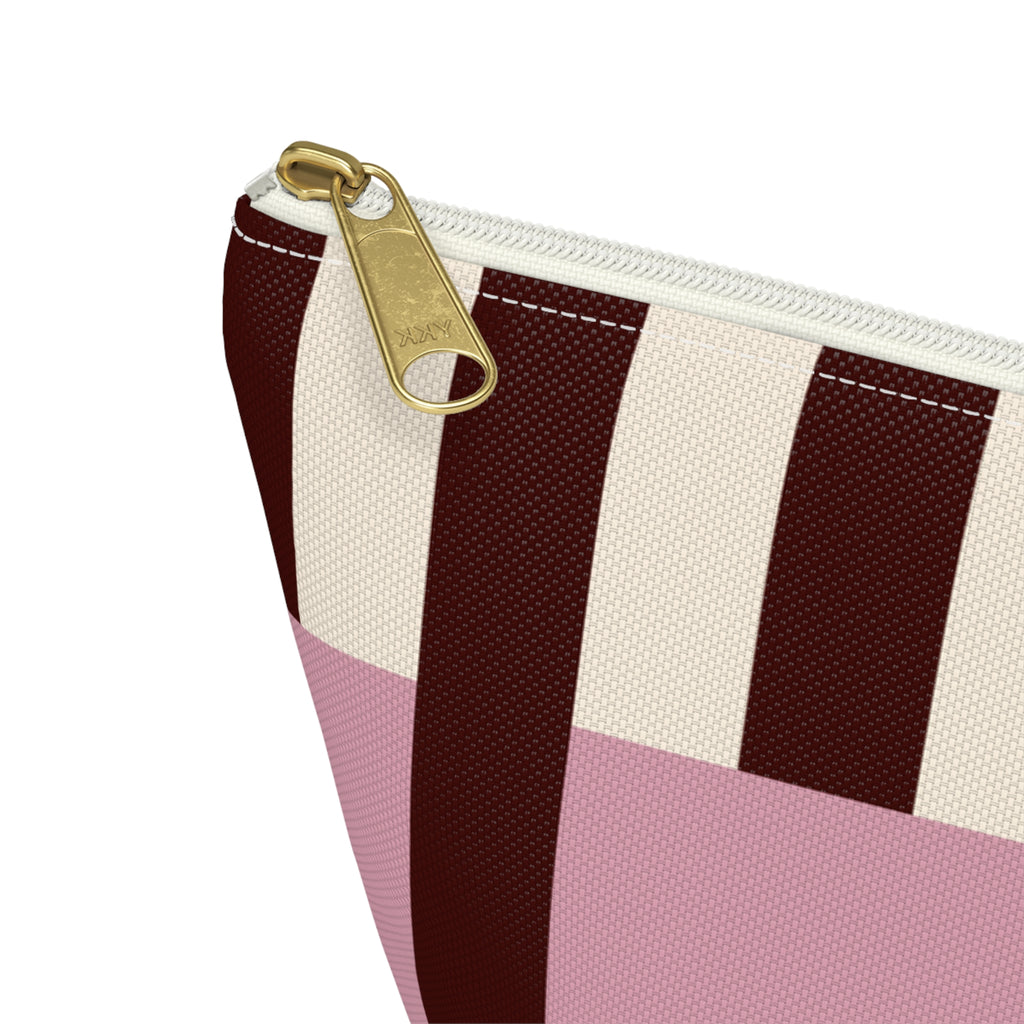 Close-up of the gold zipper pull on the pink burgundy cream striped makeup bag