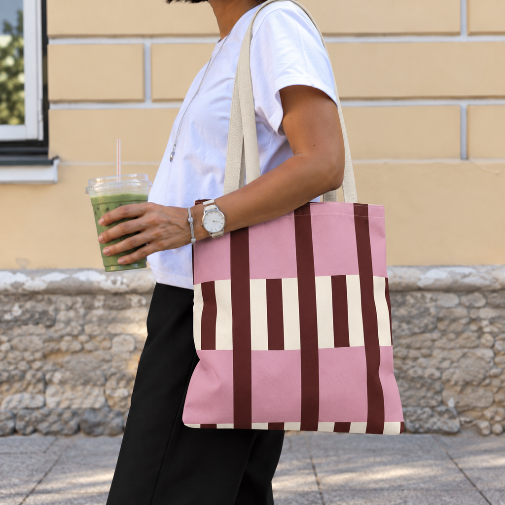 Side view of a model carrying the pink burgundy cream striped tote bag on the shoulder