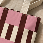 Close-up of the pink block and burgundy cream stripes with beige handle on the tote bag