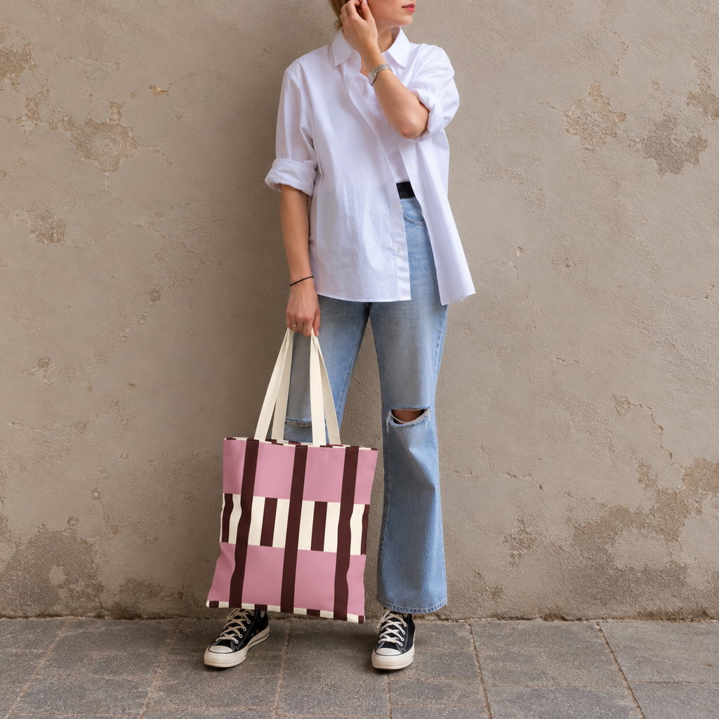 Model in jeans and a white shirt standing with the pink burgundy cream striped tote bag