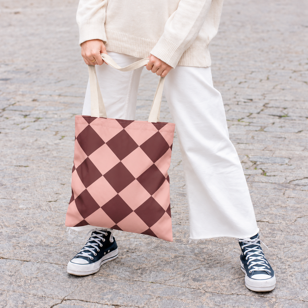 Model with white trousers holding the pink burgundy checkered tote bag