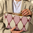 Hands holding the pink cream diamond pattern makeup bag with a perfume bottle inside
