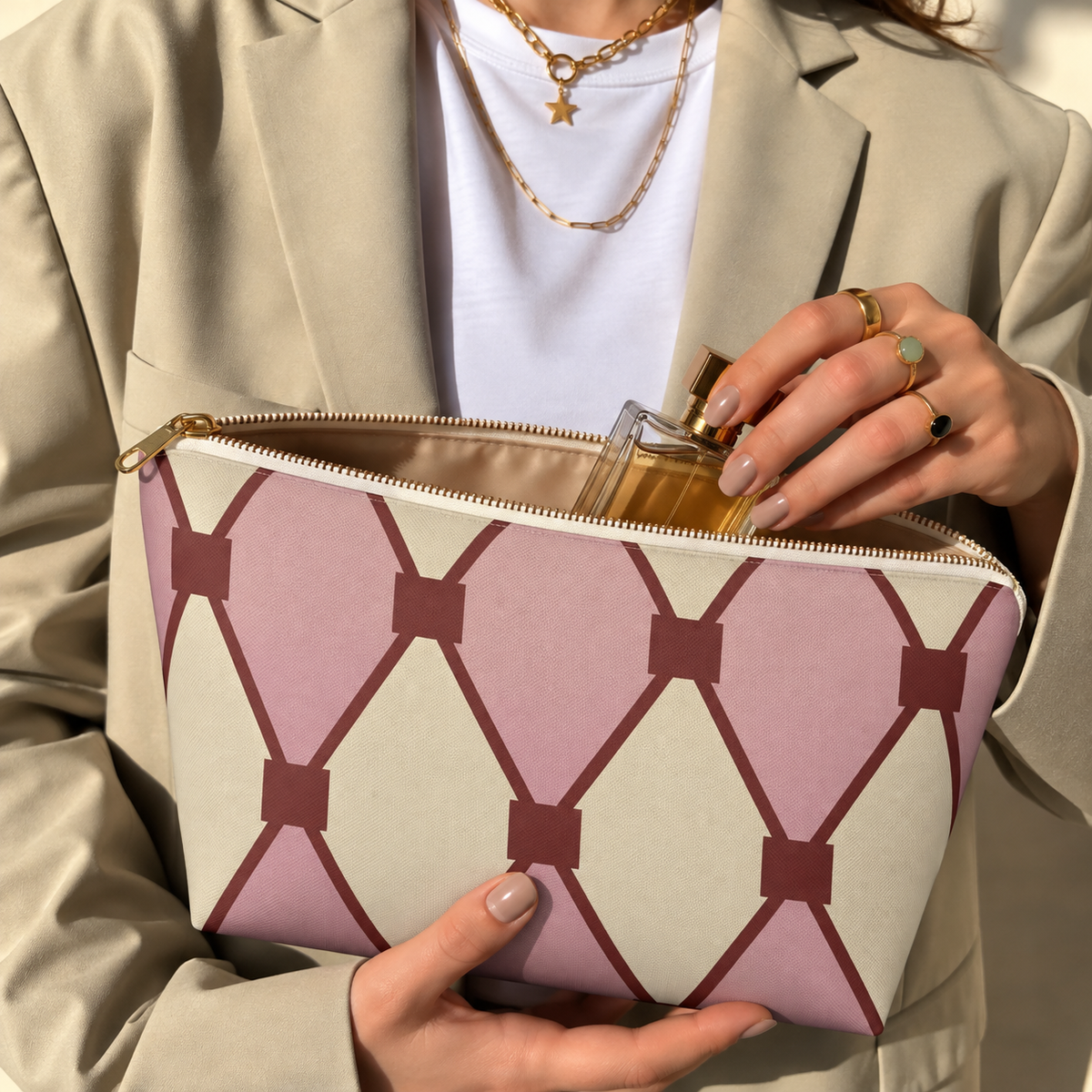Hands holding the pink cream diamond pattern makeup bag with a perfume bottle inside