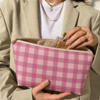 Hands holding the open pink gingham makeup bag with a perfume bottle inside
