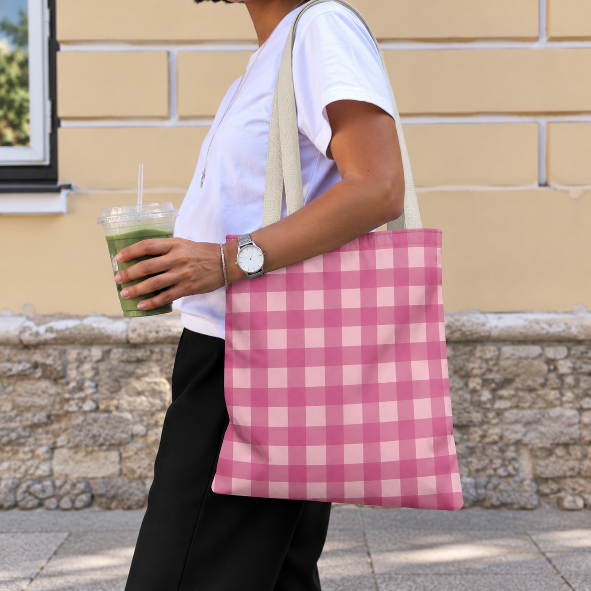 Woman with an iced drink wearing the pink gingham tote bag on her shoulder