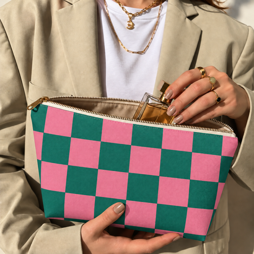 Hands holding the open pink green checkered makeup bag with a perfume bottle inside