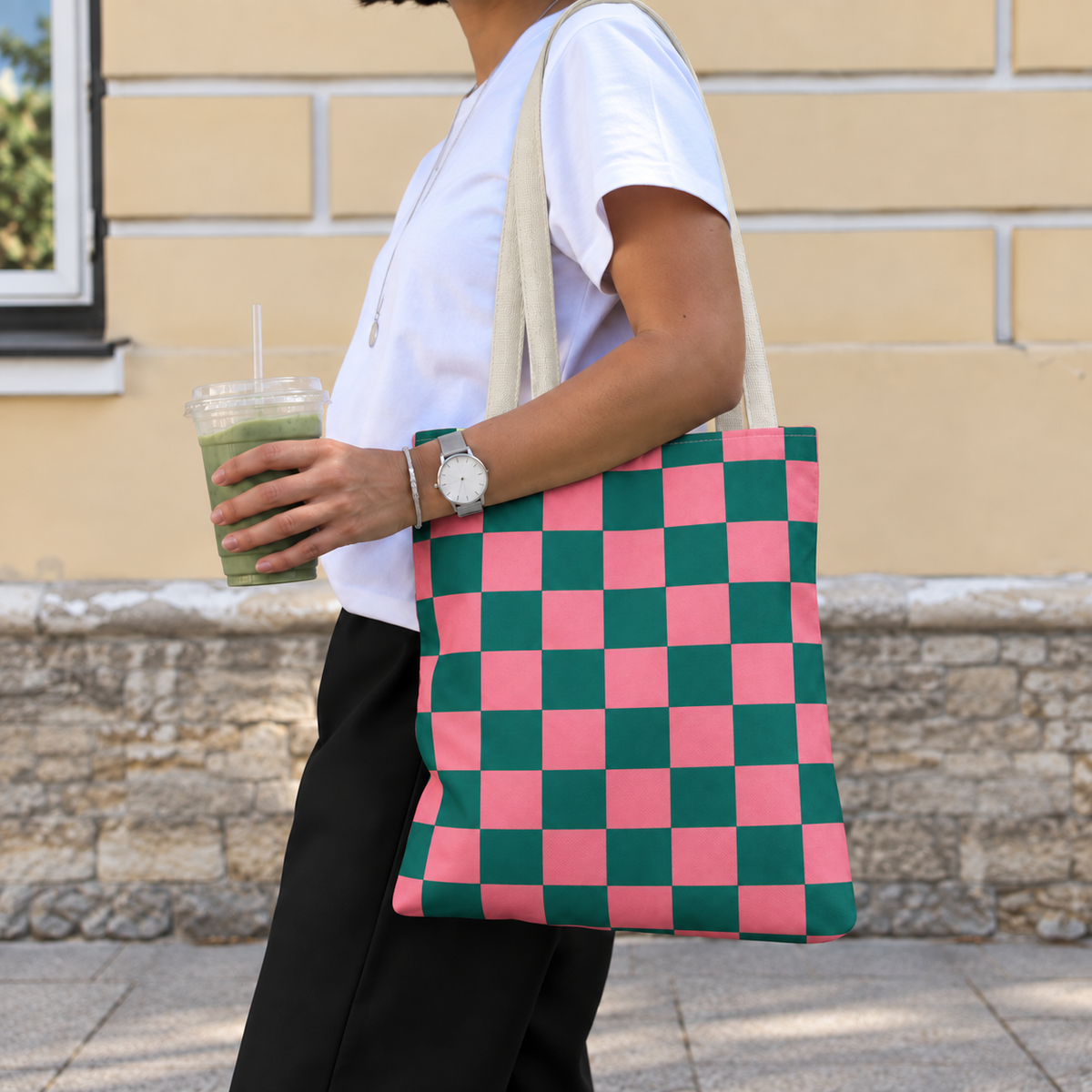 Woman with an iced drink wearing the pink green checkered tote bag on her shoulder